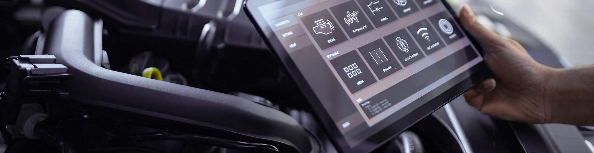 Mechanic using diagnostic tablet on car engine